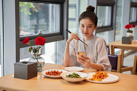 在汤泉馆美食区吃饭玩手机的青年女性背景图片