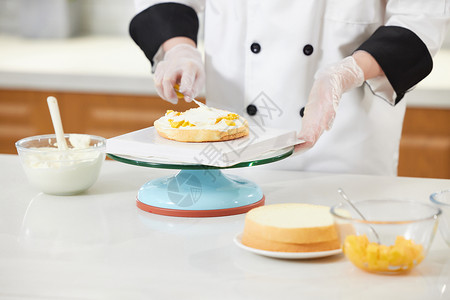 烘焙师往蛋糕胚上抹奶油特写图片