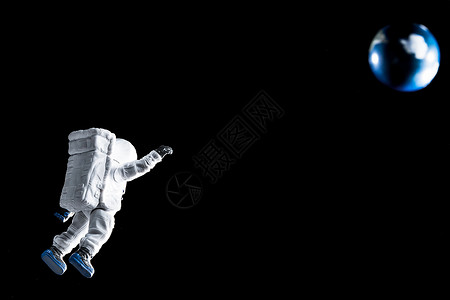 打招呼的宇航员悬浮在太空中跟地球挥手的宇航员背景