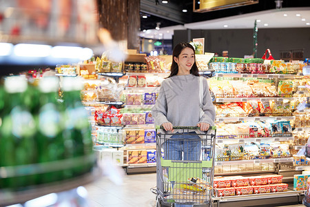 青年女性推手推车逛超市购物图片