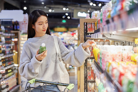 青年女性逛超市采购挑选饮品图片