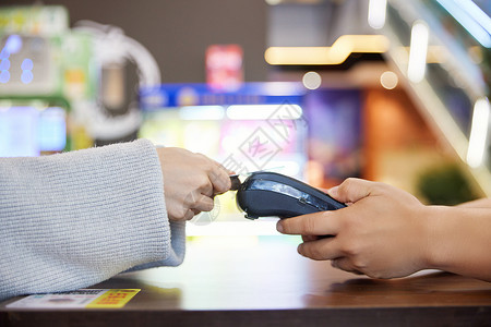 nfc移动支付青年女性超市购物POS机刷卡付款特写背景