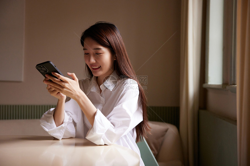 居家女性坐在客厅玩手机图片