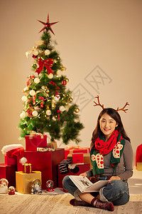 圣诞节美女微笑坐在圣诞树和礼物前背景图片