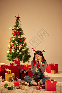 清纯可爱美女圣诞节开心的坐在圣诞树和礼物前背景图片