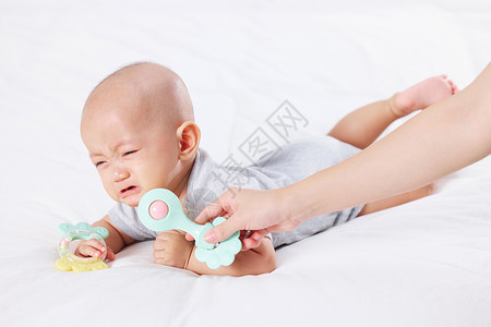 本宝宝不开心手拿玩具逗哭泣的宝宝背景