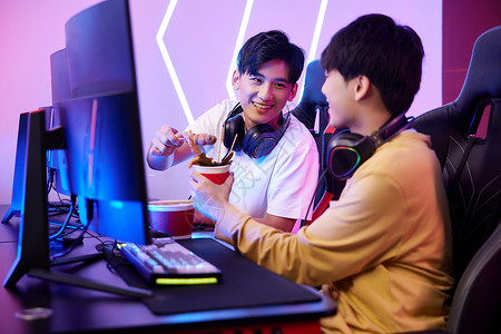 青年男性网吧里打电脑游戏吃关东煮高清图片