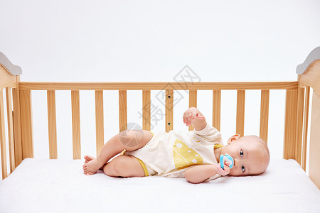 可爱宝宝在婴儿床里吃奶嘴图片