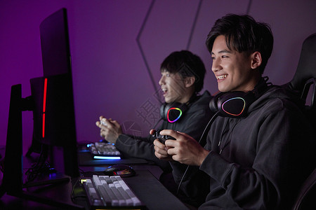 青年男性熬夜通宵使用手柄玩电脑游戏背景图片