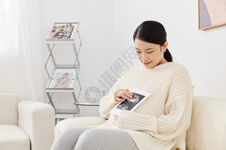 孕期妈妈居家坐沙发上看婴儿B超图像图片