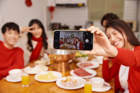 年轻人新年聚会吃饭拿手机自拍特写背景图片