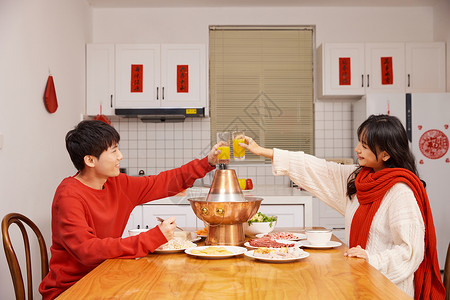 年轻情侣居家跨年吃火锅举杯图片