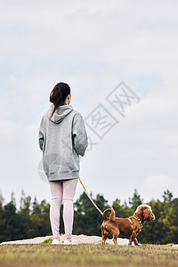 人和宠物背影牵着狗绳的运动少女和萌宠泰迪的背影背景