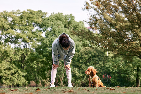 在公园牵着狗跑步休息的少女图片
