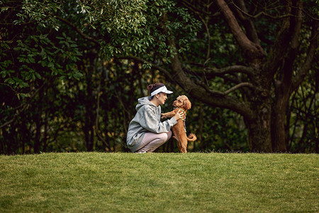 在公园草地里和泰迪一起玩耍的运动少女图片