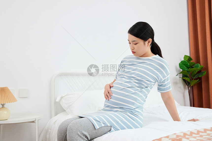 坐在床上摸孕肚的产前孕妇图片