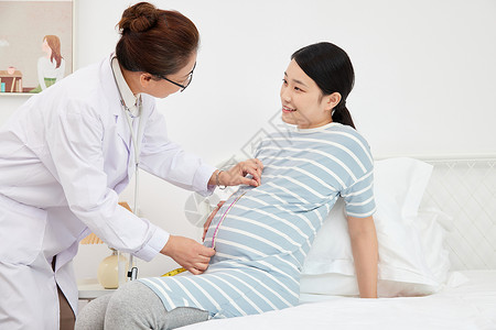 妇产科医生为孕妇测量孕肚背景图片