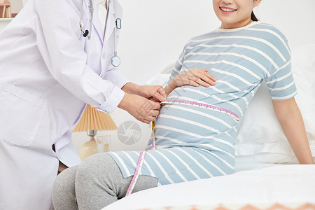 女性妇科妇产科医生为孕妇测量孕肚特写背景
