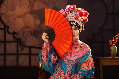 国粹戏曲京剧美女手拿红纸扇遮面背景图片