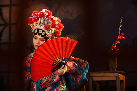 国粹戏曲京剧美女手拿红纸扇遮面背景图片