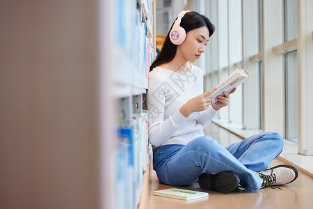 女学生在图书馆看书听音乐高清图片