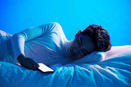 家居物联网年轻男性拿着手机睡觉背景