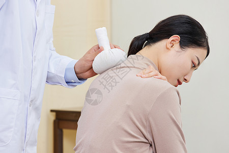 男中医给女顾客肩部使用艾草理疗图片