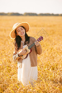 在稻田里弹奏尤克里里的女性图片