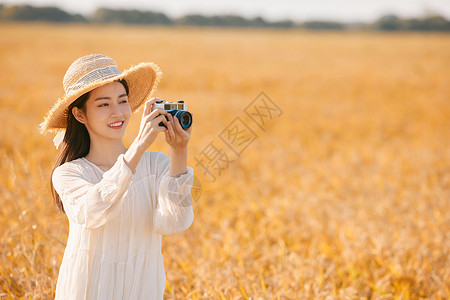 拿着照相机站在稻田里的女性背景图片