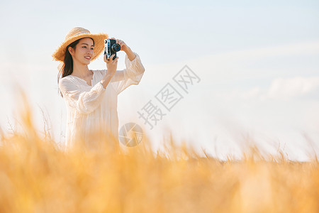 穿着连衣裙的女性站在稻田里拍照高清图片