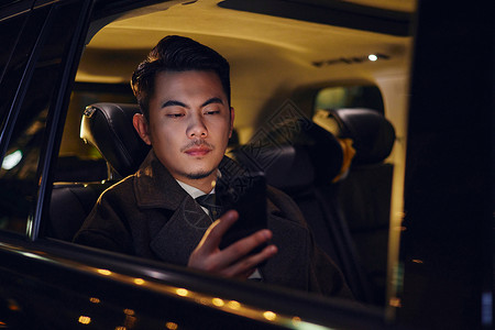 人坐在车里商务男士夜晚车里玩手机背景