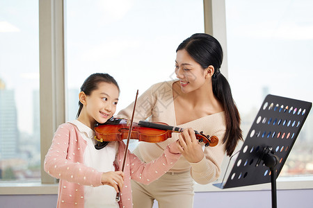 音乐老师教小女孩拉小提琴背景图片