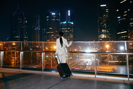 都市女性夜晚拉着行李箱孤独背影图片