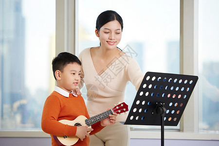 吉他培兴趣班女老师指导小男孩弹尤克里里背景