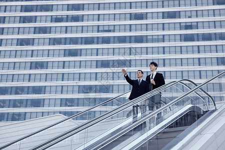 商务人士手指站在高楼前手指远方的商务人士形象背景