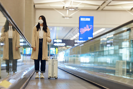 电梯口罩机场拖行李的女性背景