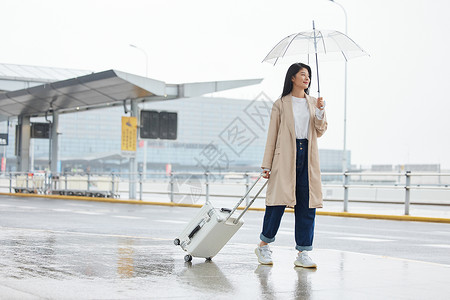 水上拖伞下雨天撑伞拖行李的女性背景