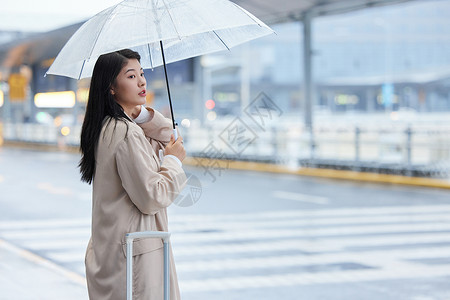 雨天撑伞等车的女性背景图片