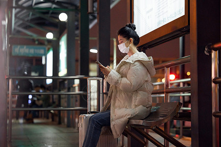 戴口罩的美女夜间出行坐在站台等待公交车高清图片