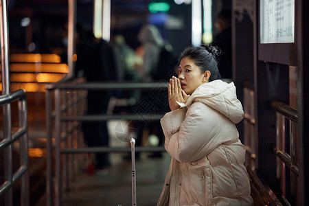  美女寒冬夜间出行坐在站台等待公交车图片
