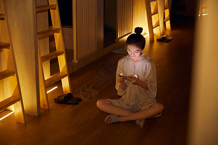年轻美女在汤泉馆休息区玩手机游戏图片