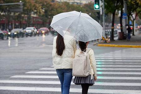 放学接送下雨天母女撑伞牵手过人行道背影背景