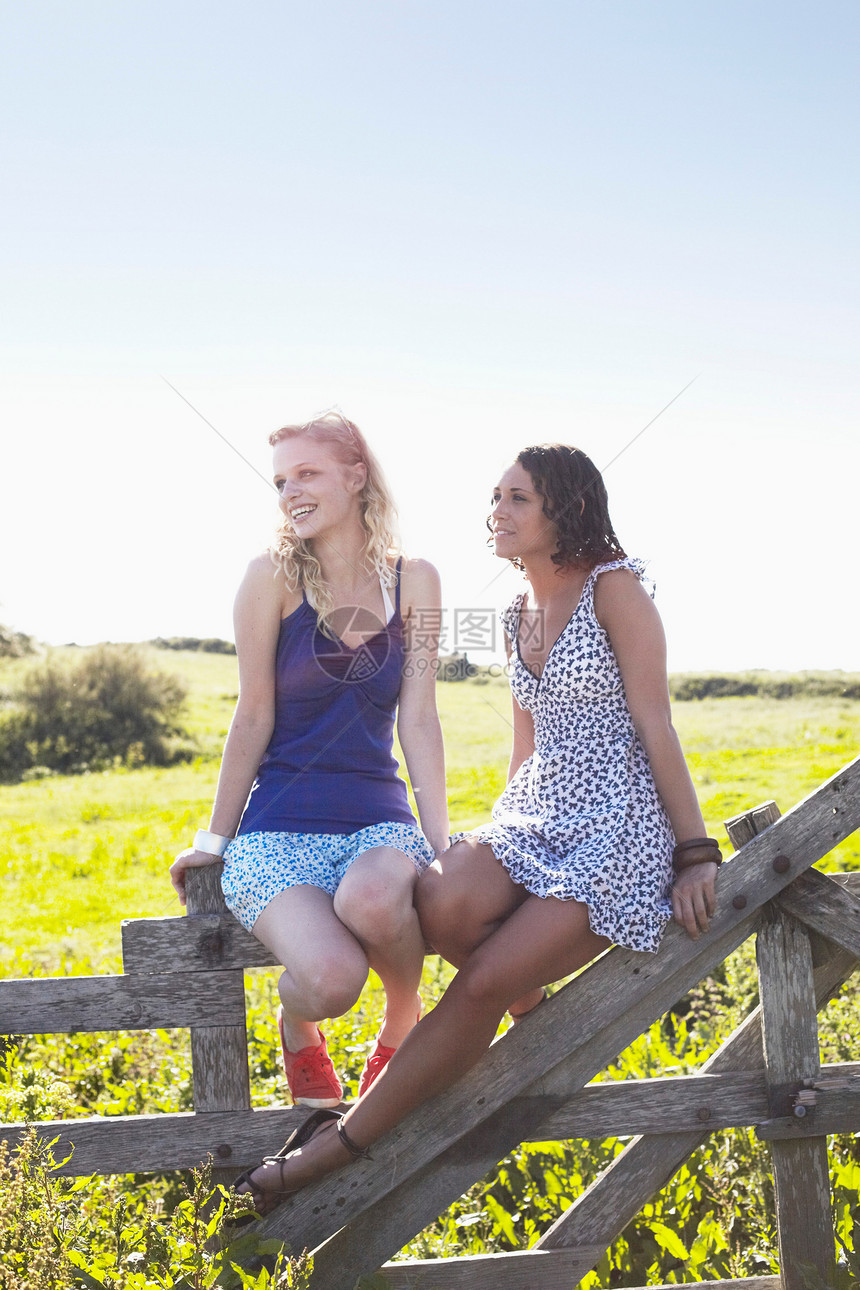 两名女孩坐在围栏上图片