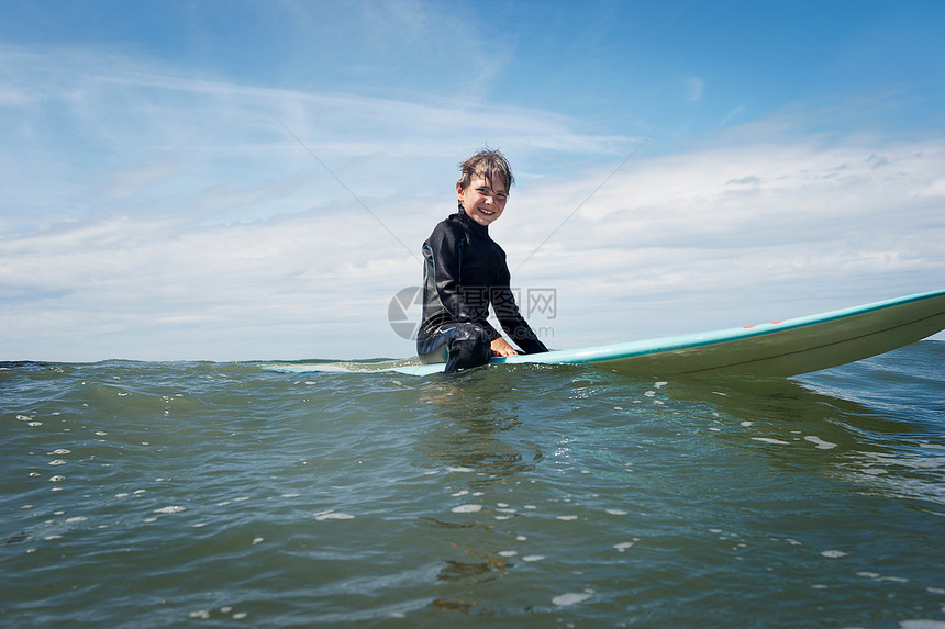 坐在海上冲浪板的小男孩图片