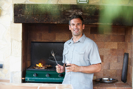 微笑的男人站在烧烤旁图片