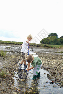 两个男孩在溪流中用蚊帐钓鱼图片