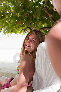 海滩上在树下聊天的情侣图片