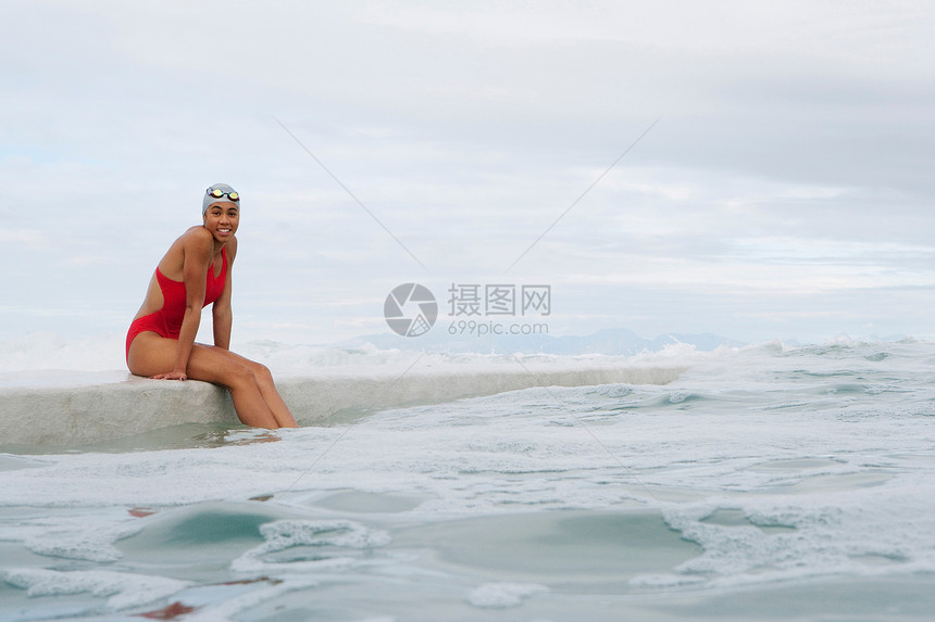 坐靠水岸的泳衣女性图片