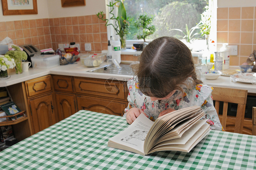 小女孩在厨房桌上看书图片