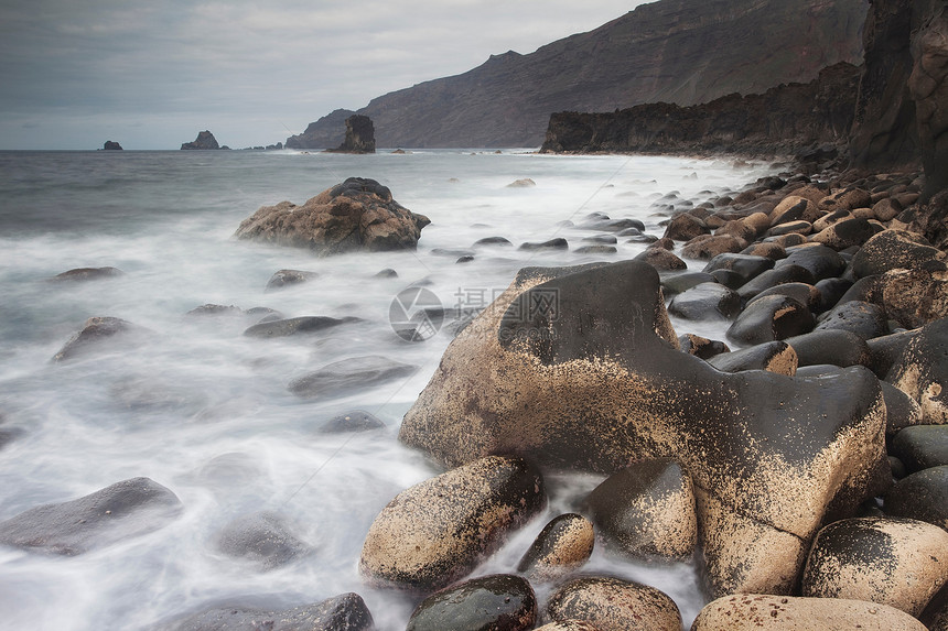 冲洗海滩岩石的波浪图片